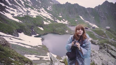 a young woman hiker climbs mountains and photographs landscapes on camera. transfagarasan, carpathian mountains in romania