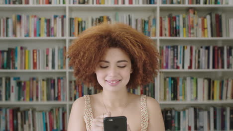 Portrait-African-American-woman-student-smiling-bookshelf-library-university