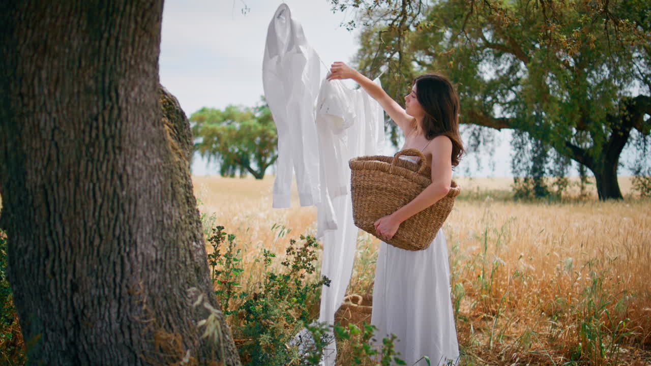 Involved girl putting laundry at rope summer nature. Woman holding wicker basket