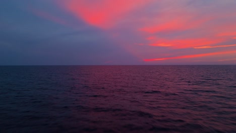 ocean at sunset with vibrant pink and purple hues reflecting on the calm water, creating a serene view