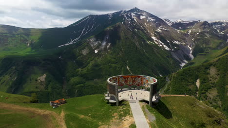 cinematic drone shot of the arch of friendship of peoples and the caucasus mountains in gudauri georgia