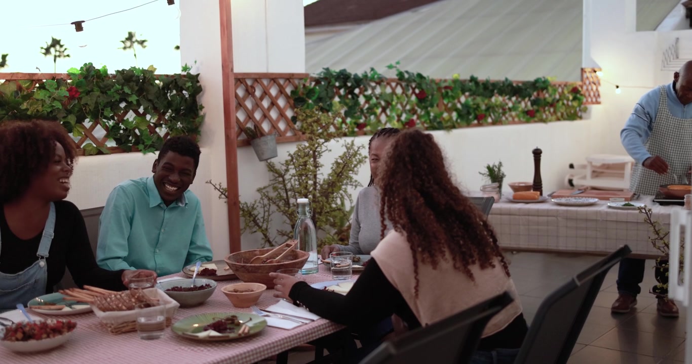 Happy Multi-Generational Family and Friends Enjoying Dinner on a Rooftop Terrace