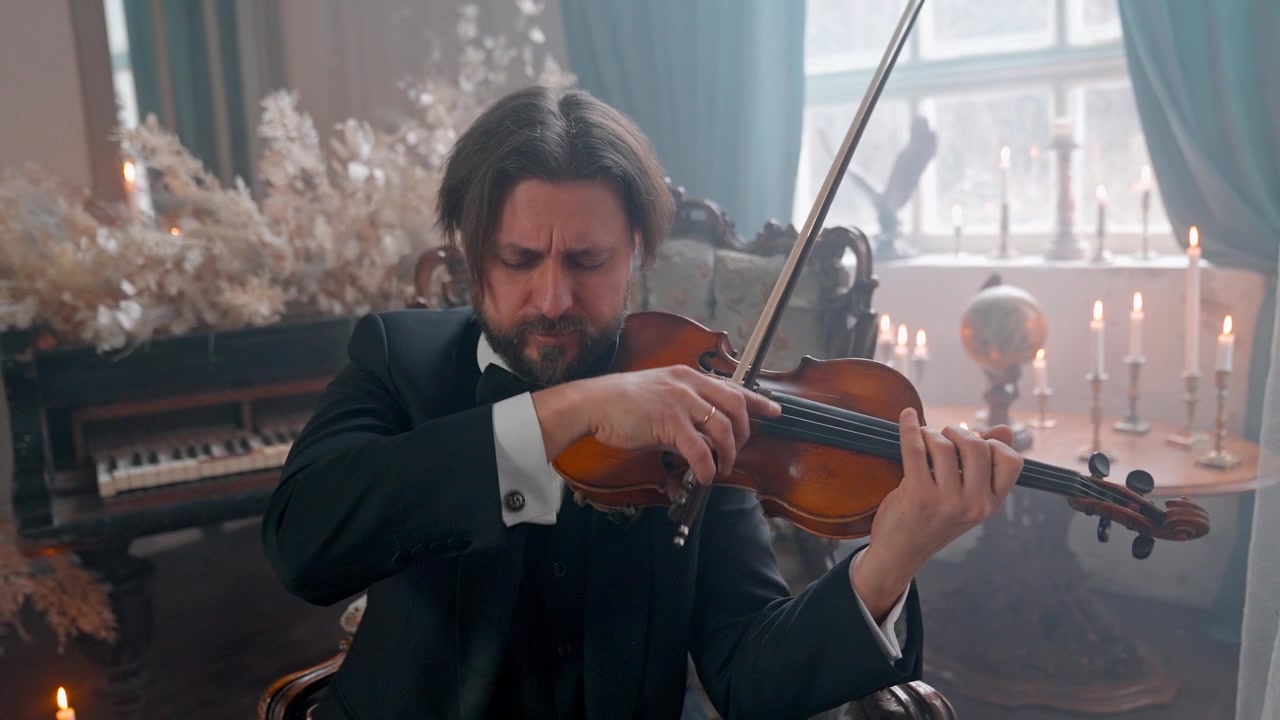 Elegante musicista che suona il violino in una stanza vintage illuminata a lume di candela