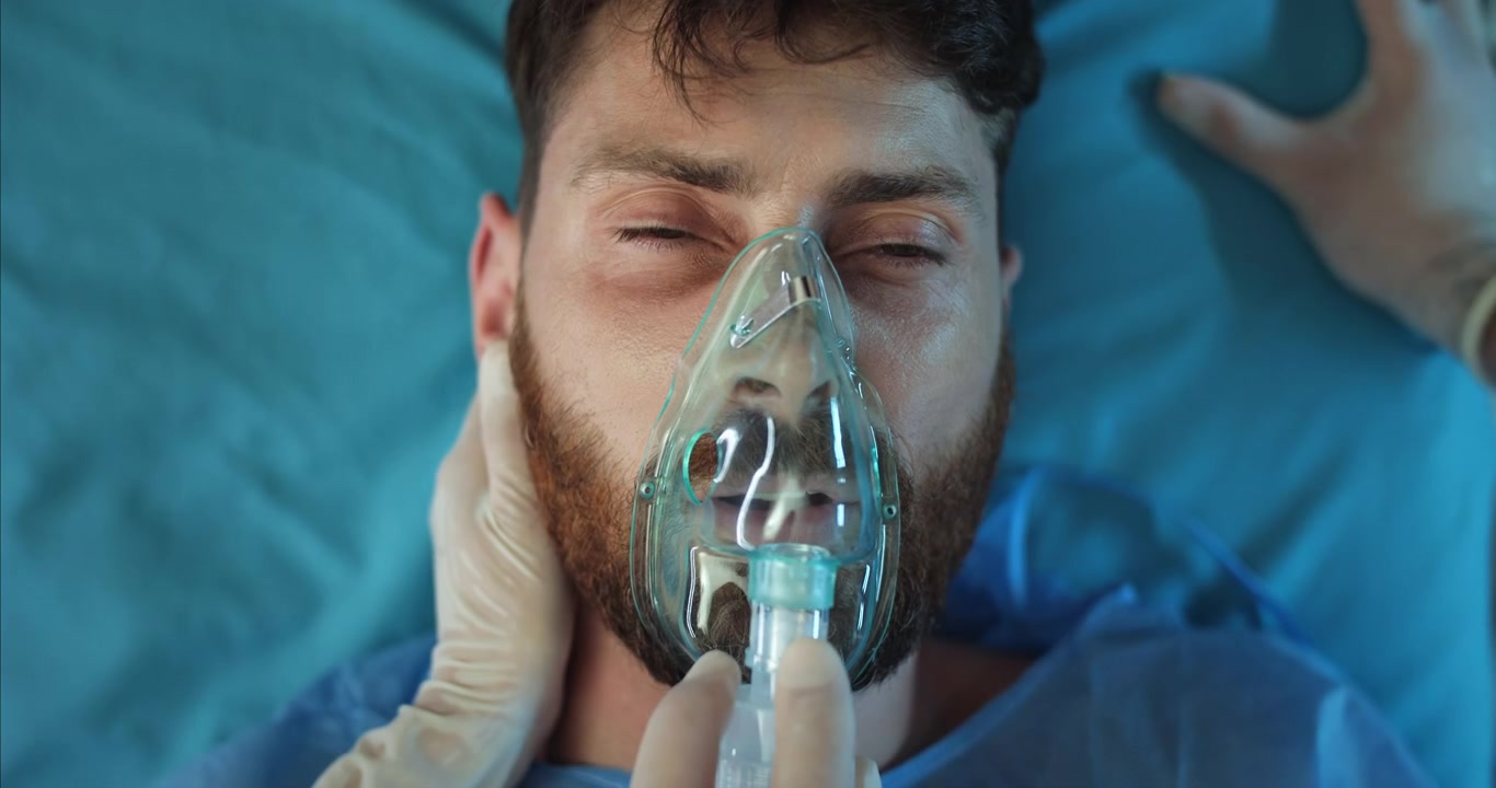 Personale medico che applica una maschera per l'ossigeno a un paziente maschio incosciente