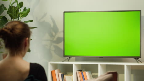 woman watching tv in a living room with a green screen