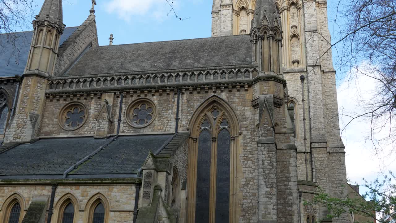 Chiesa di St Mary Abbots a Kensington, Londra, con alta torre in pietra e facciata gotica. Vista diurna che mostra i dettagli architettonici contro un cielo blu.