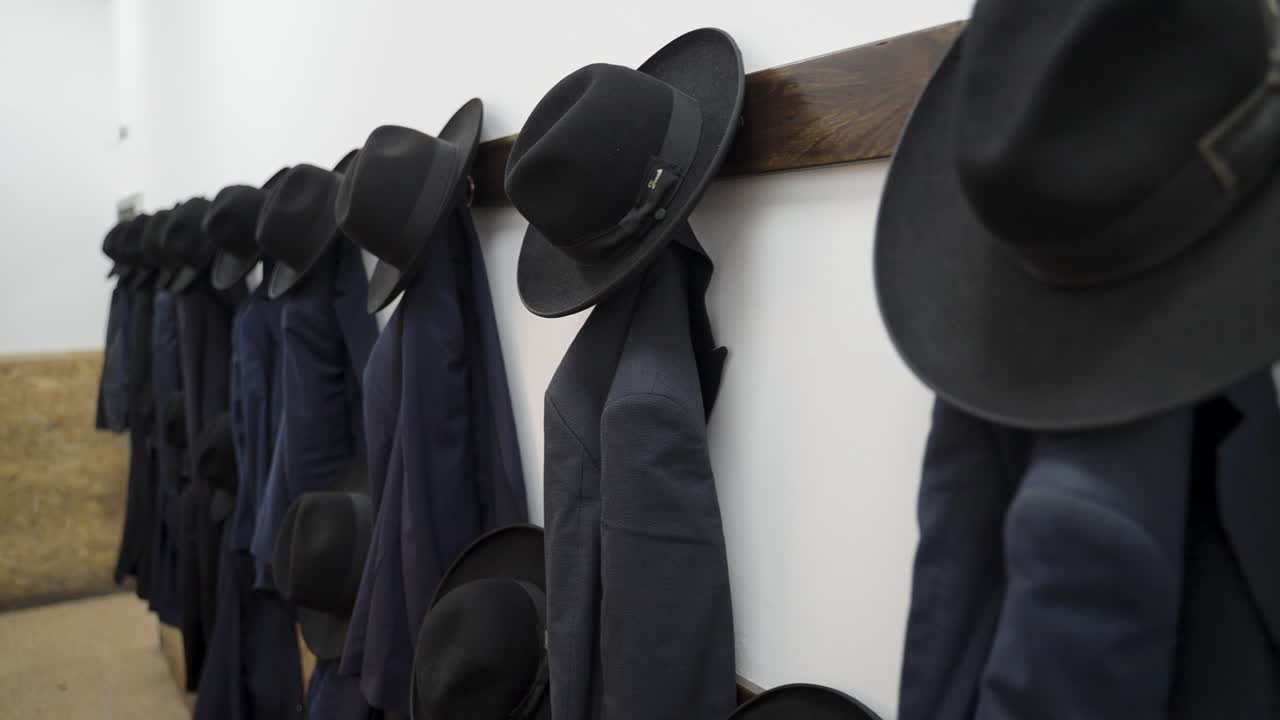 Forward Camera Movement Capturing Orthodox Jewish Coats and Hats Hung on Wooden Rack in Yeshiva, Israel