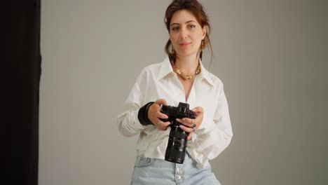 joven fotógrafa posando con la cámara en el estudio