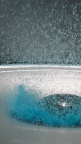 bright blue powder flies up near dust cap. movement of modern dynamic speaker diaphragm. acoustic experiment on study of sound waves against black wall macro