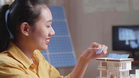 mujer examinando una casa modelo con paneles solares