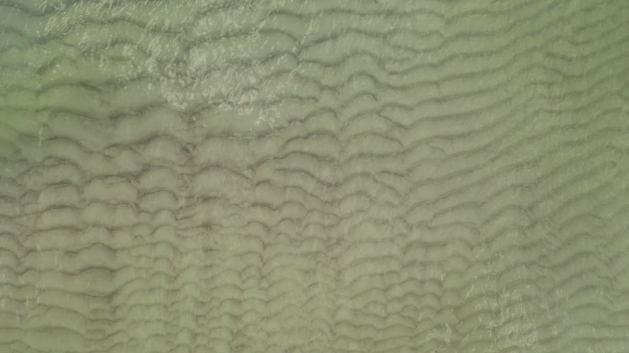 antena: plano medio de la vista superior de las olas en la orilla poco profunda y derramándose sobre la arena