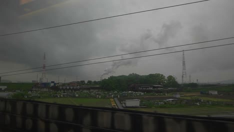 Blick-Auf-Das-Industriegebiet-Durch-Das-Zugfenster-An-Einem-Bewölkten-Tag,-Zeitlupe,-Japan