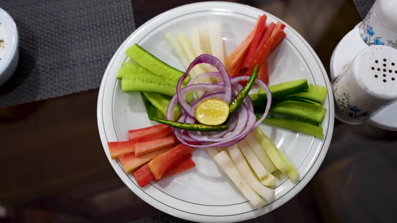 Assorted sliced vegetables with onion, chili, and lemon centerpiece served at a restaurant. Pakistan