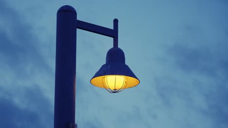 un poste de luz se alza desafiante contra un cielo que se oscurece mientras las nubes pasan lentamente