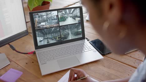 African-american-female-security-officer-watching-business-cctv-camera-views-on-laptop,-slow-motion