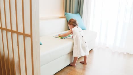 little girl wearing dress looking at colorful pictures of book