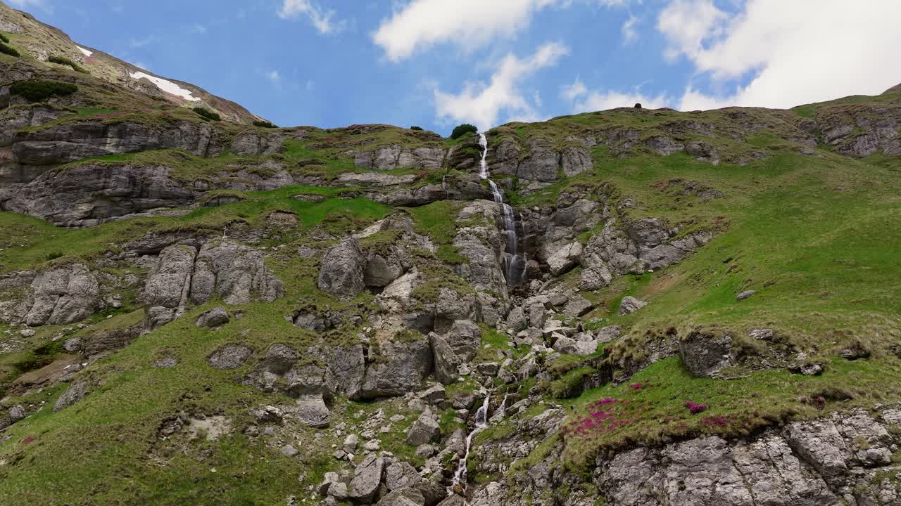 Cascata di montagna a più livelli che scende a cascata da scogliere aspre in una giornata di sole, ripresa statica