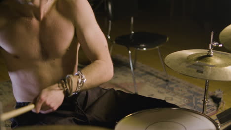 Energetic-shirtless-male-drummer-with-beard-playing-drums