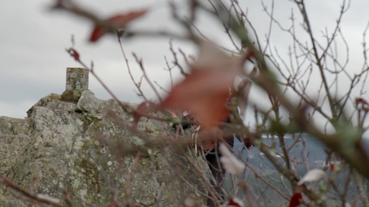 женщина-пешеход идет по скалистому холму с видом на пик