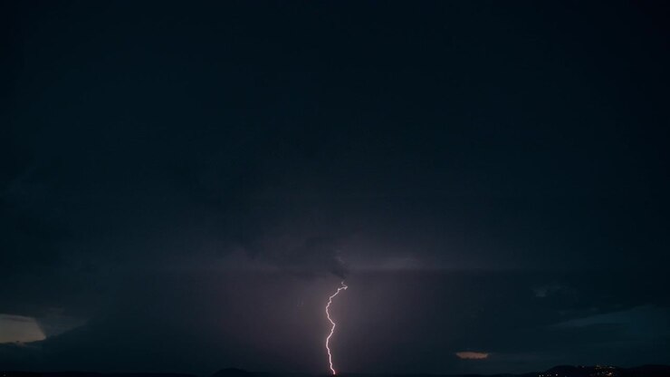 Fulmine frastagliato che squarcia il cielo scuro e nuvoloso.