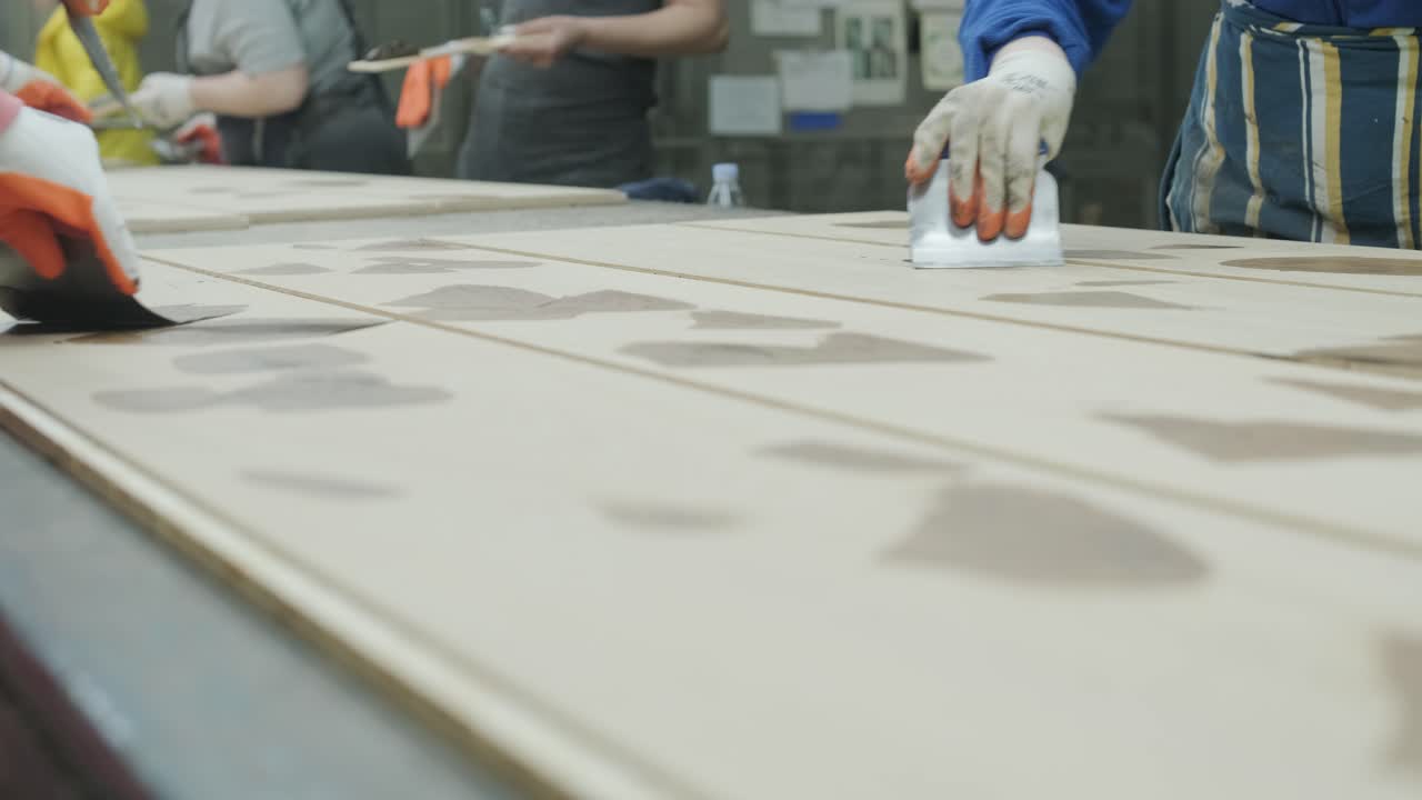 Workers Applying Glue or Filler to Wooden Panels in a Factory