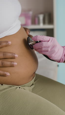 doctor examining pregnant woman with stethoscope