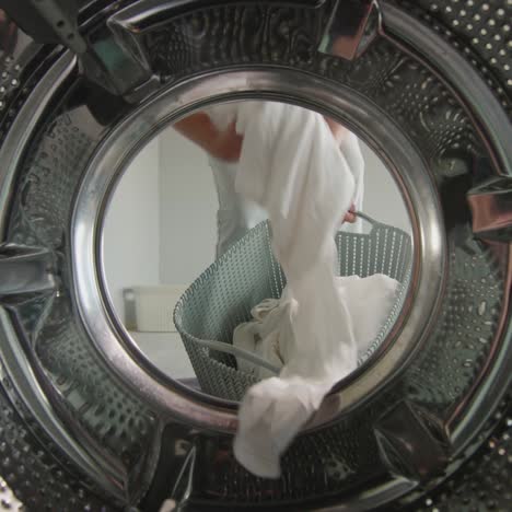 A-woman-pulls-clean-washed-white-linen-from-the-washing-machine