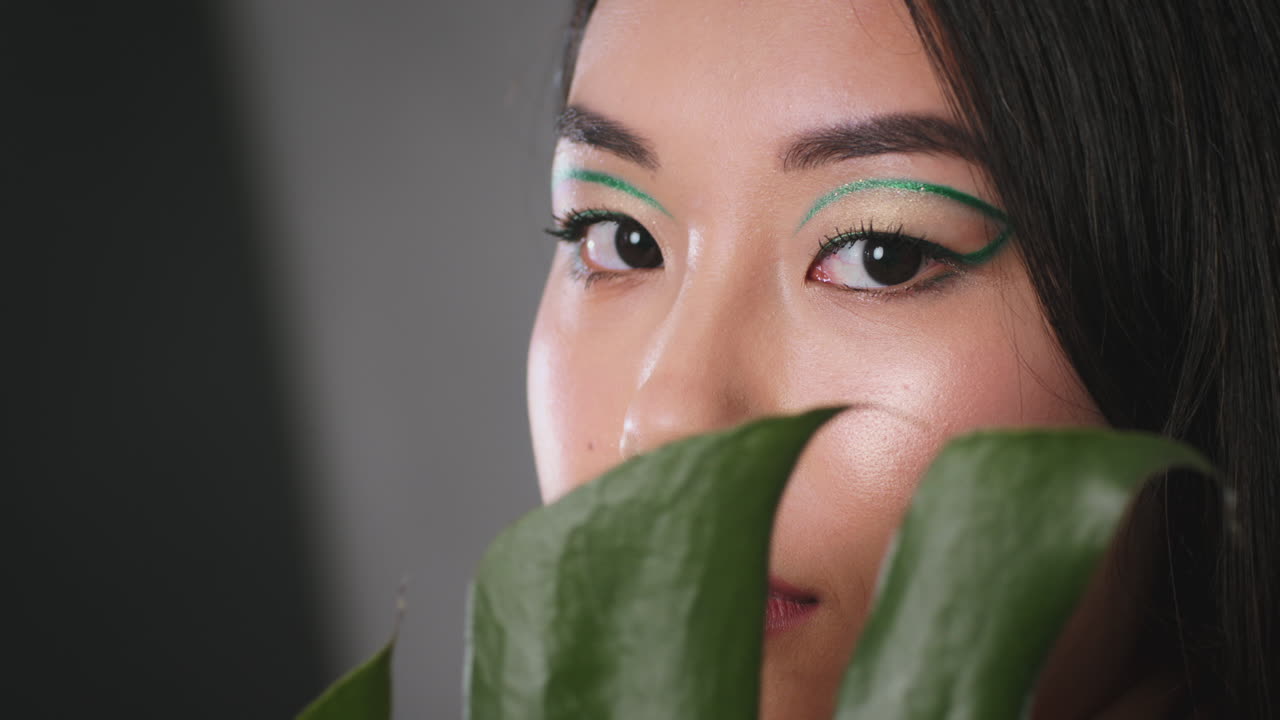 Close-up portrait of a woman with elaborate green eye makeup