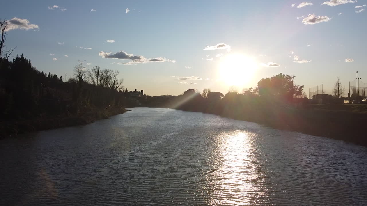 Approaching Sunset drone flies above the Arno river. Girone small town near Fiesole Florence, in the Tuscany region of Italy. December 2019