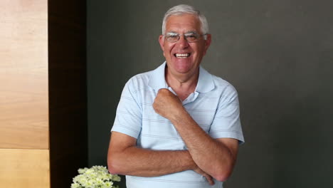 hombre mayor de pie y sonriendo a la cámara