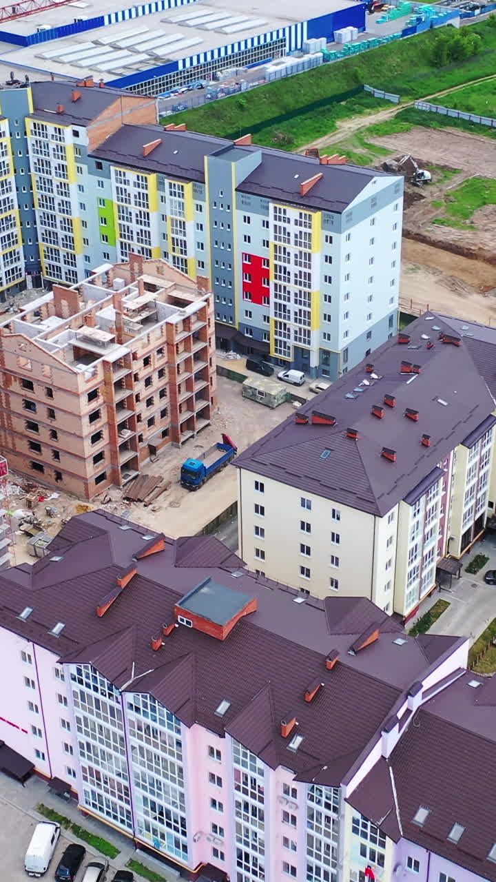 Construction of a new residential complex. Modern multi-storey buildings build in the city. Construction site with high cranes. Aerial view. Vertical video