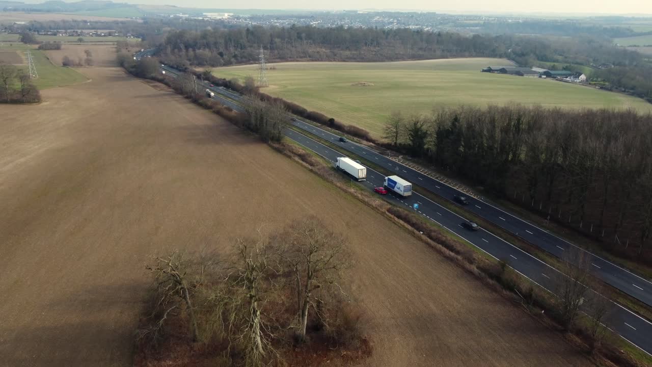 Aerial view of highway with vehicles passing through fields and trees