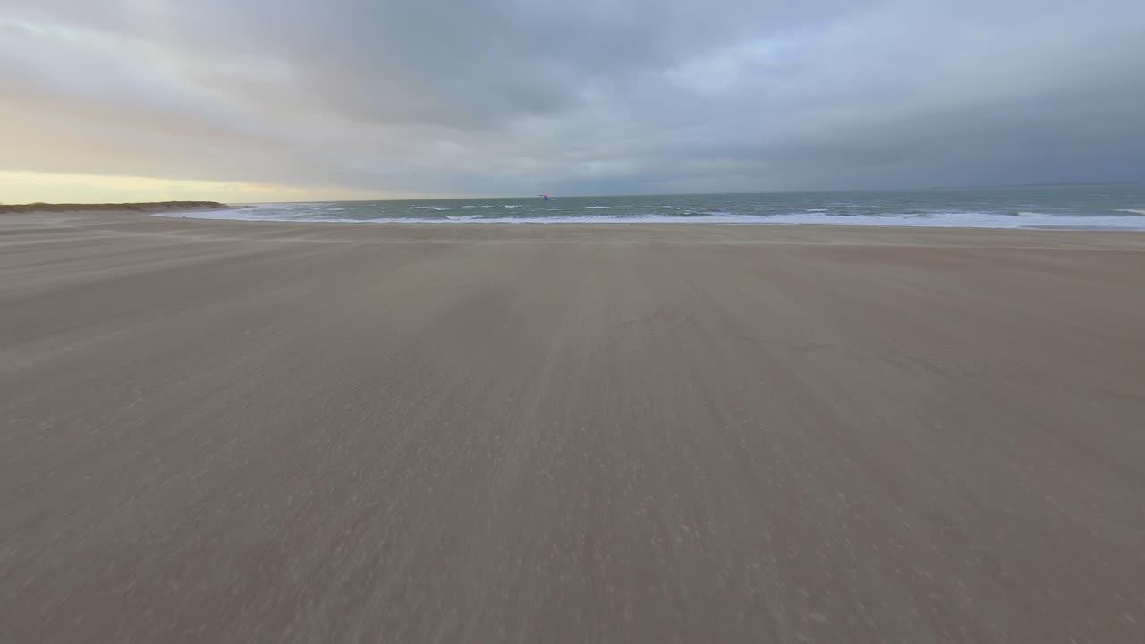 Fast shot towards a kitesurfer who jumps at the end. Aerial shot