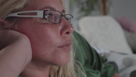 retrato de una mujer madura aburrida con gafas viendo la televisión en el sofá