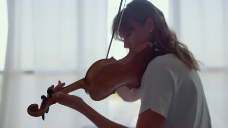 Girl-practicing-music-on-violin-with-bow.-Violinist-playing-chords-on-violin