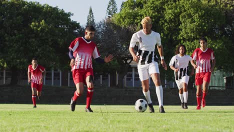 Video-Einer-Vielfältigen-Gruppe-Männlicher-Fußballspieler-Auf-Dem-Feld,-Die-Fußball-Spielen