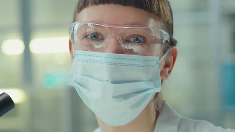 portrait of female scientist in mask and glasses in lab
