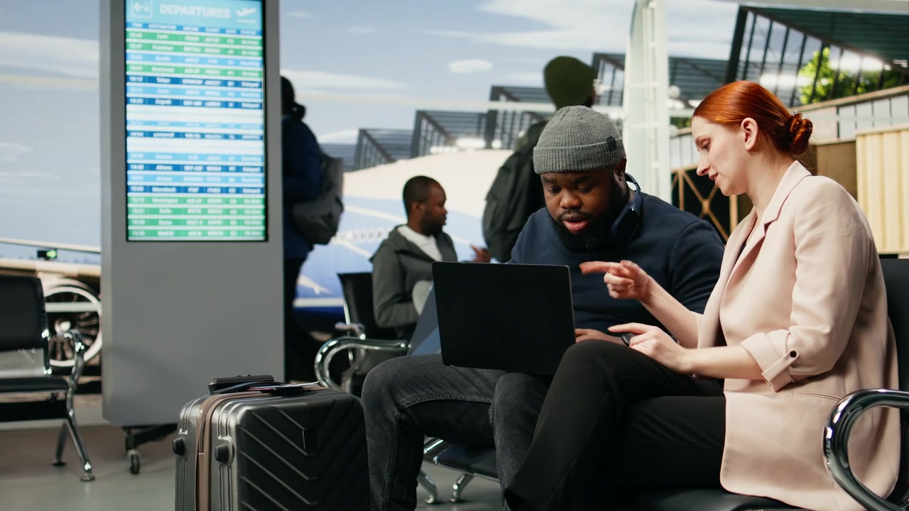 Team of diverse consultants typing on laptop in airport lounge