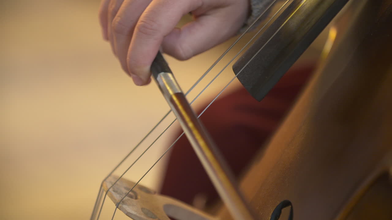 Primo piano di un musicista che suona il violoncello con un archetto