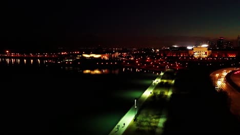 vuelo bajo a lo largo de la costa urbana por la noche con reflejos de luz en el agua