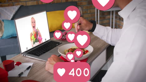 iconos del corazón y números crecientes contra el hombre que almuerza mientras tiene una videollamada en la computadora portátil