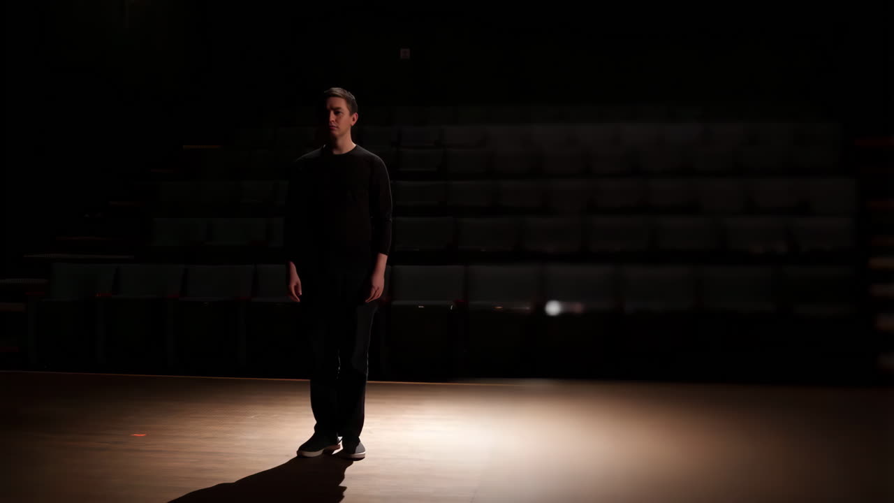 Man standing in a spotlight on a dark stage