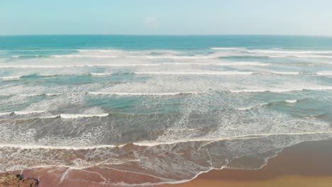 Olas-Suaves-Rompiendo-En-La-Playa-De-Arena,-Impresionantes-Aguas-Turquesas