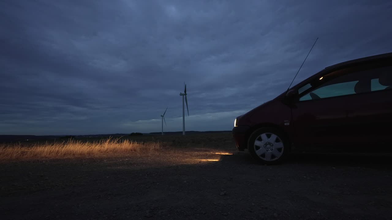 풍력 터빈과 함께 에서 낮과 밤의 타임 스, 자동차 헤드 라이트가 경로를 밝히고