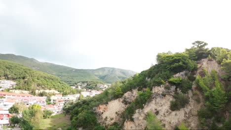 FPV-drone-flying-over-green-mountains-revealing-a-football-pitch-in-Greece