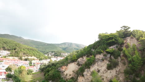 drone fpv volando sobre montañas verdes revelando un campo de fútbol en grecia