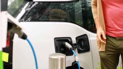 hombre cargando un coche eléctrico en la estación de carga 4k