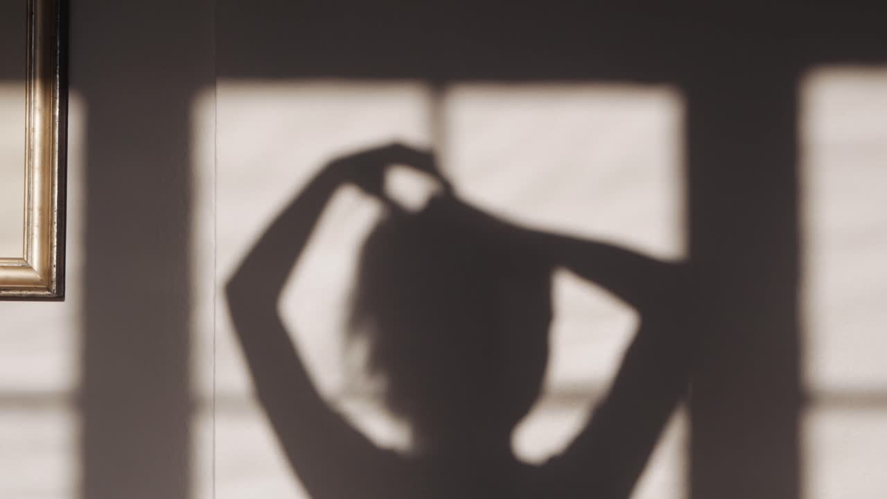 집에서 그녀의 머리에서 포니 테일을 만드는 여자의 그림자