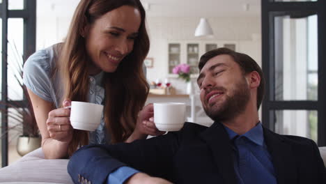 smiling couple drinking tea at home together during coffee break