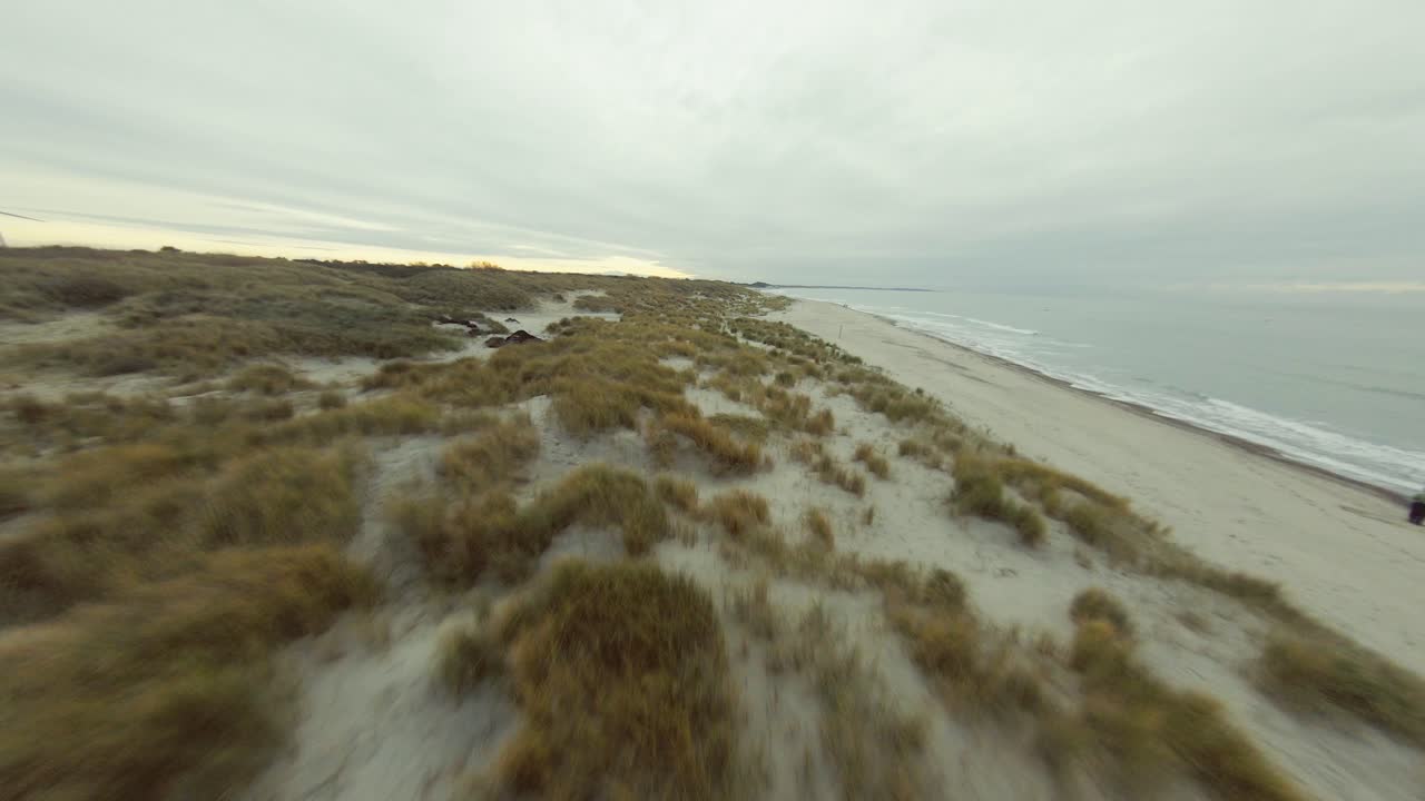 drone volando bajo sobre las dunas en una playa holandesa